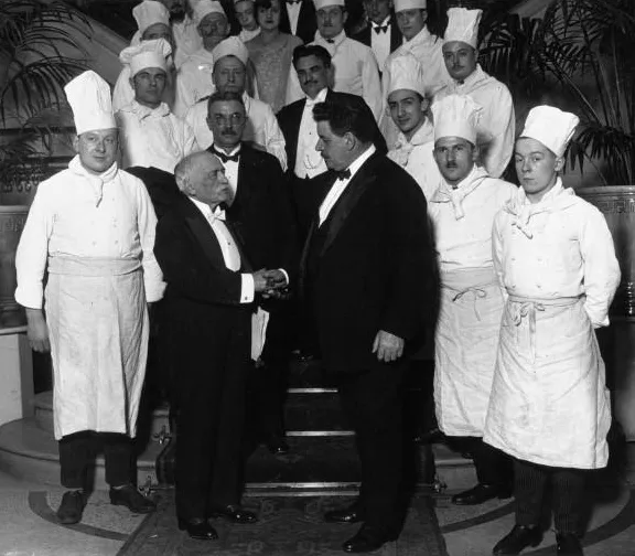 Fotografía en blanco y negro de 1928 del chef francés Auguste Escoffier conversando con el primer ministro Édouard Herriot durante un banquete.