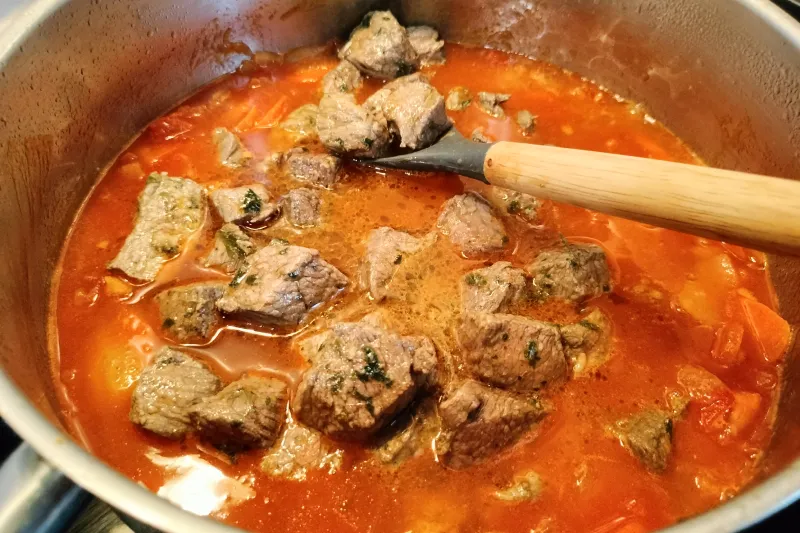 Añadiendo la carne a un guiso de carne con papas canaria.