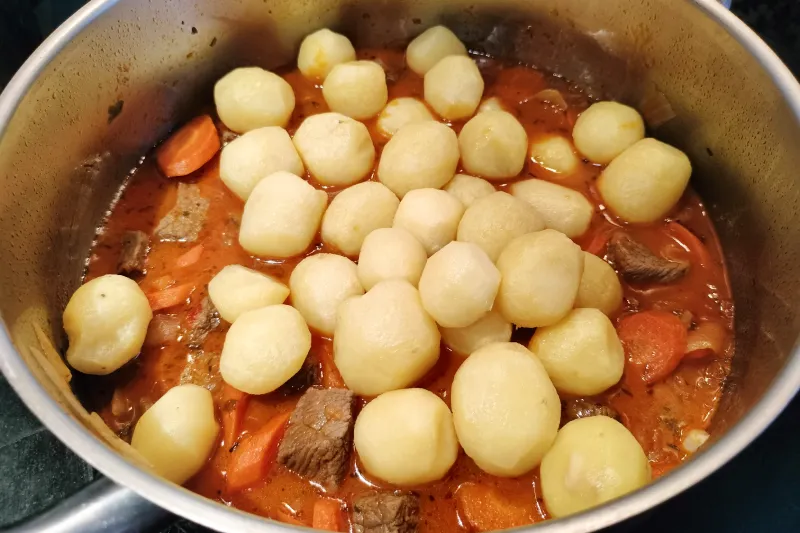 Añadiendo las papas a un guiso de carne con papas canaria.