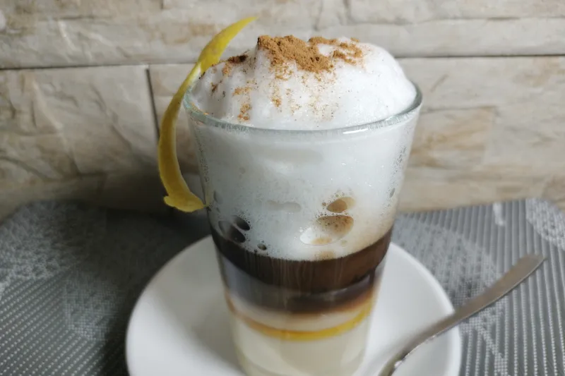Un barraquito terminado y coronado con limón y canela molida.