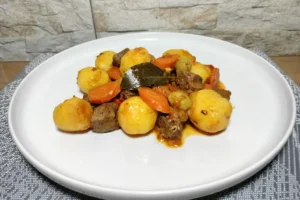Un plato con carne con papas canaria.
