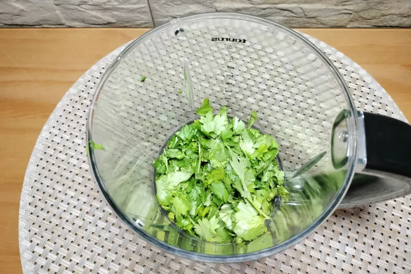 Cilantro picado en un vaso de batidora para hacer mojo verde de cilantro.