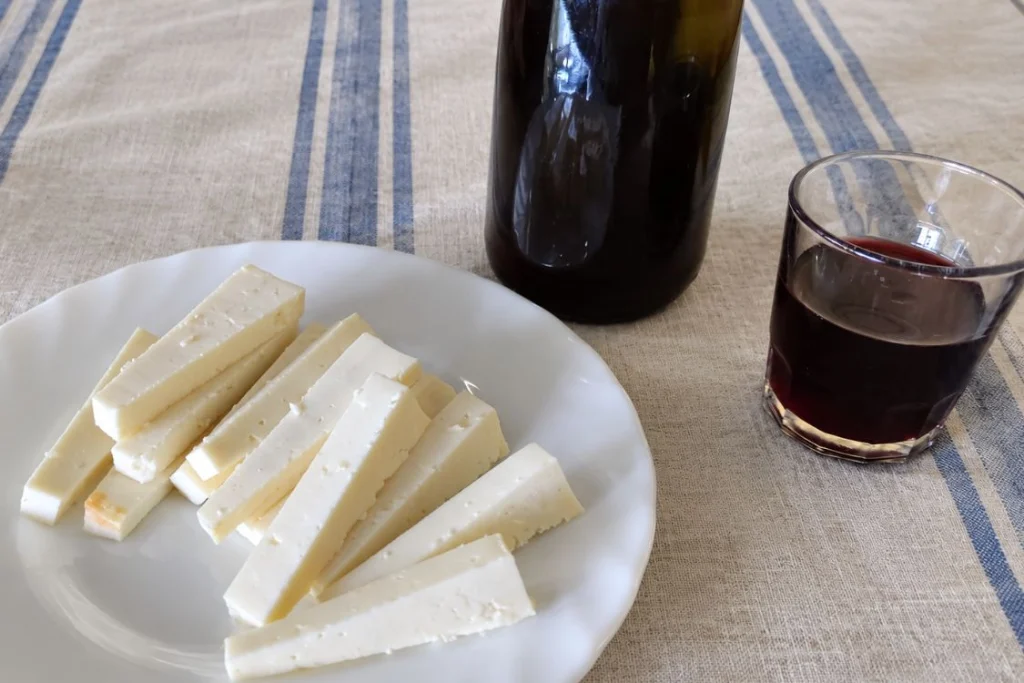 Un enyesque de queso blanco para acompañar a un vaso de vino tinto.