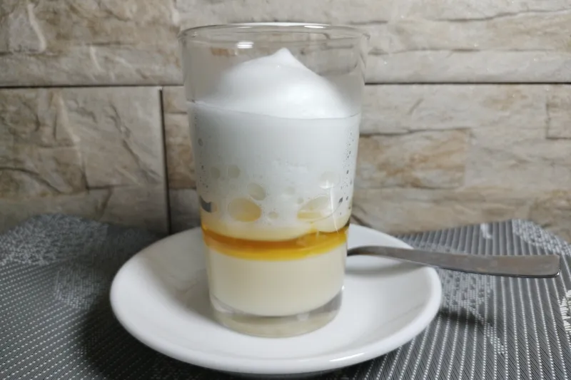 Un vaso con leche condensada, licor 43 y espuma de leche para hacer un barraquito casero.